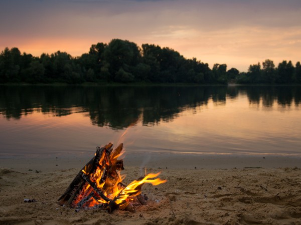 A campfire on a sandy beach at sunset
