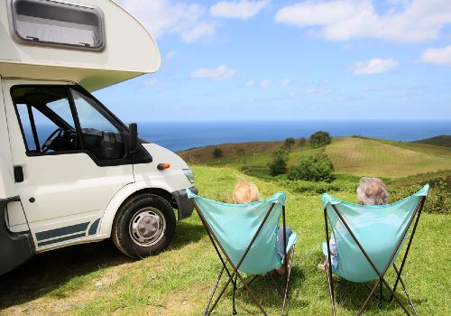 A couple relaxing in folding camping chairs near the rented RV