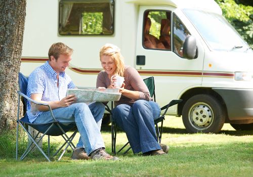A couple relaxing outside a motor home on their vacation