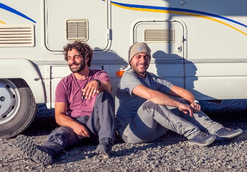 Friends laughing outdoors near a camper