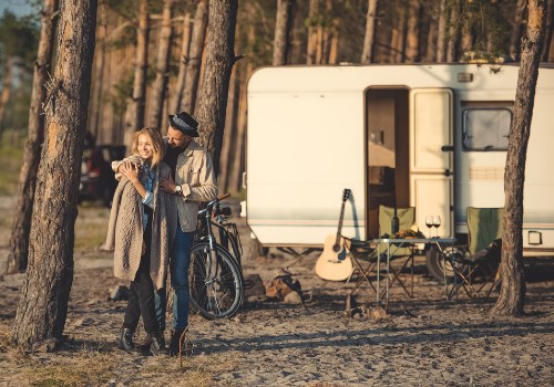 A happy couple in a forest with a travel trailer