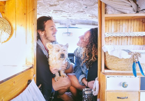 A happy couple with a dog having fun in a vintage van